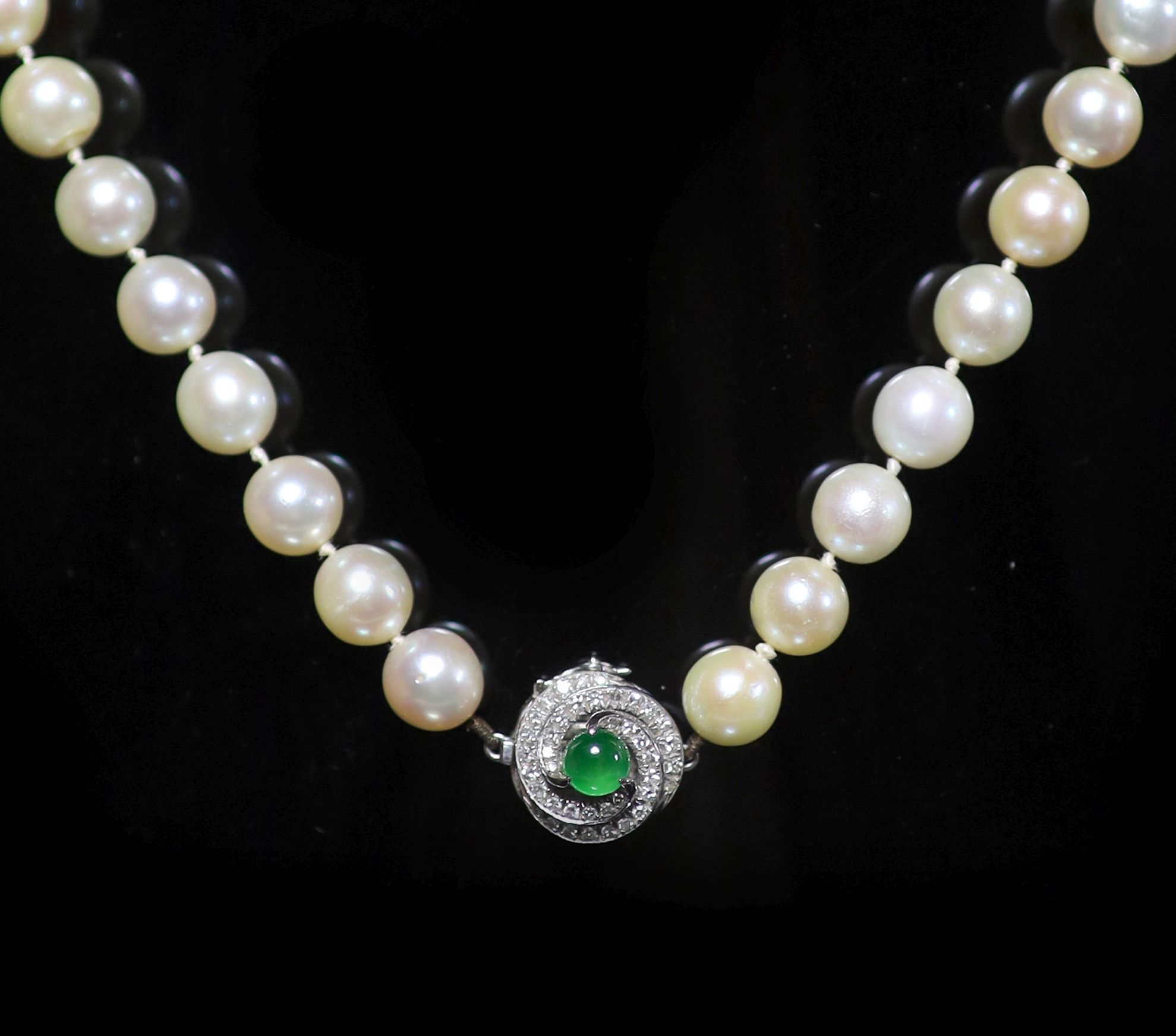 A single strand uniform cultured pearl necklace with diamond and cabochon emerald set clasp,